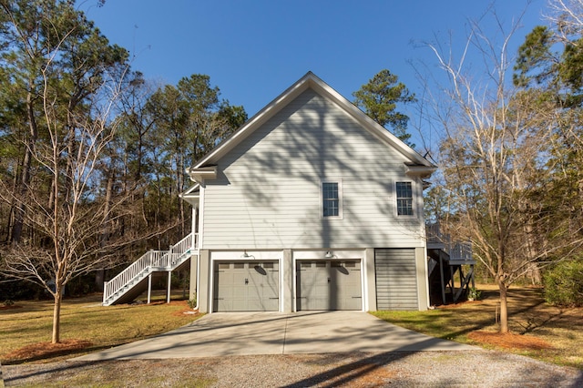 view of property exterior with stairs, concrete driveway, a yard, and a garage