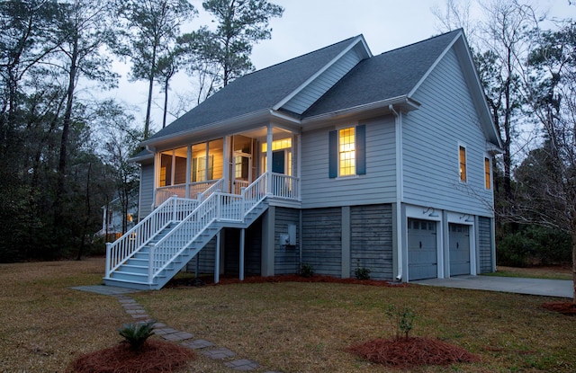 view of front of home with stairway, a porch, a front yard, a garage, and driveway