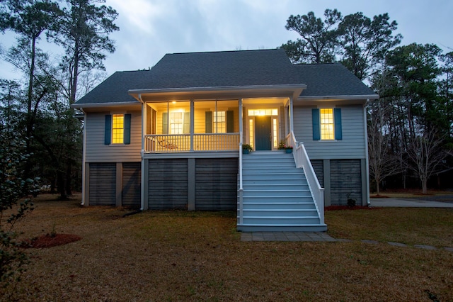 view of front facade featuring a front lawn, a porch, stairs, and roof with shingles