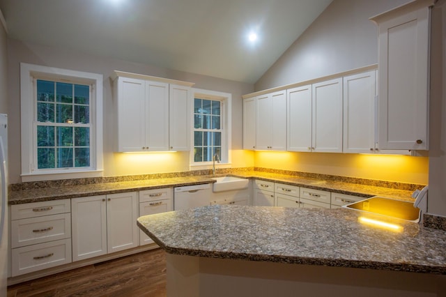 kitchen featuring dishwasher, dark stone countertops, white cabinets, and a sink