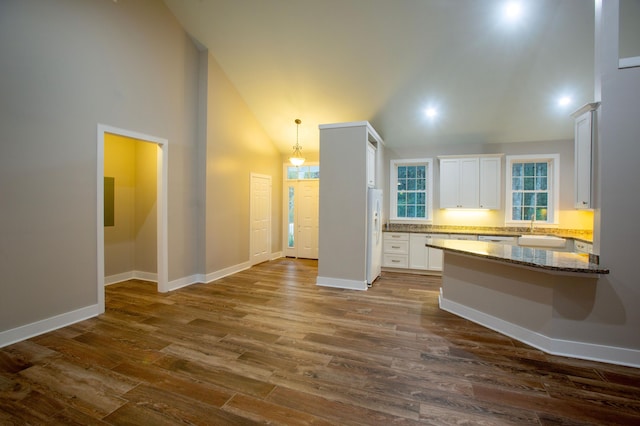 kitchen with white cabinetry, dark wood-type flooring, white refrigerator with ice dispenser, and baseboards