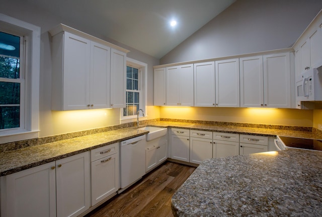 kitchen with white appliances, dark wood-style floors, a sink, vaulted ceiling, and white cabinets