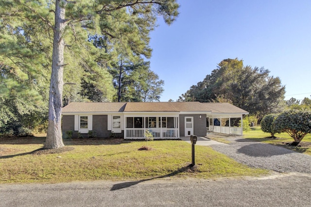 ranch-style house featuring a carport, covered porch, and a front lawn