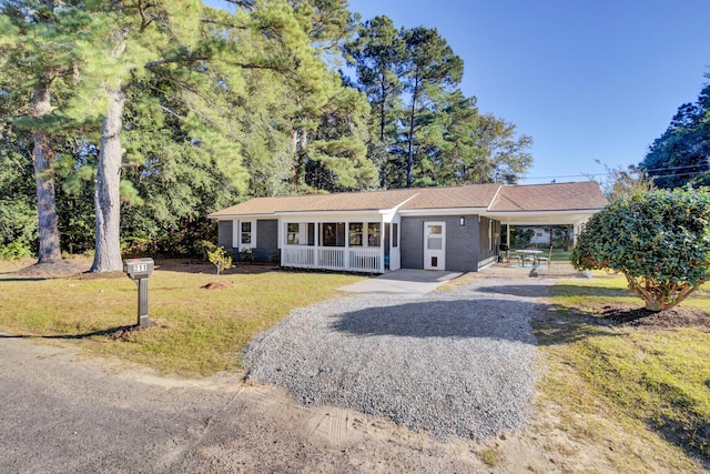 single story home with a front lawn, covered porch, and a carport