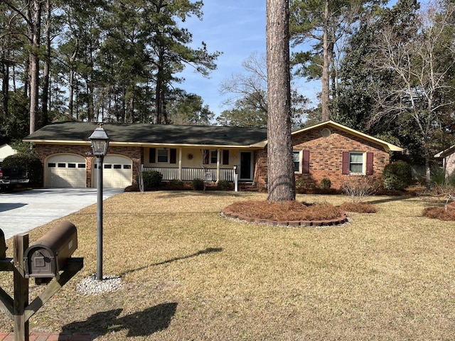 ranch-style home featuring a garage, covered porch, and a front yard