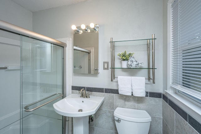 bathroom with toilet, sink, tile walls, and walk in shower
