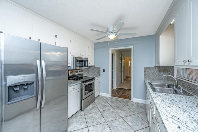 kitchen with sink, tasteful backsplash, stainless steel appliances, light stone countertops, and white cabinets