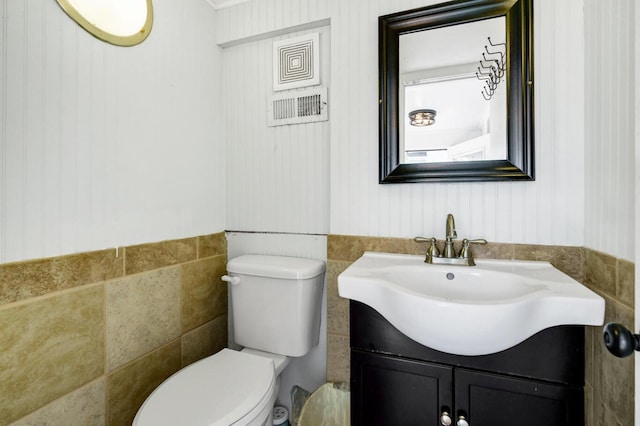 bathroom featuring vanity, tile walls, and toilet