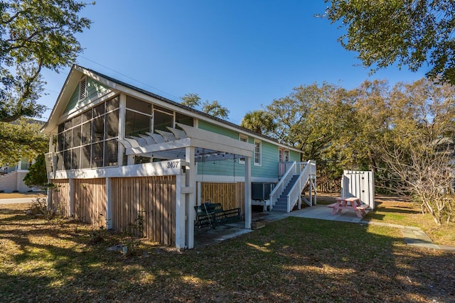 exterior space featuring a pergola, a patio area, a sunroom, and a lawn