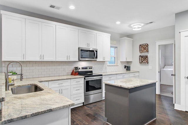 6190 Button Bush Dr, Ravenel, SC 29470 - kitchen with stainless steel appliances, a sink, dark wood finished floors, washer / dryer, and decorative backsplash