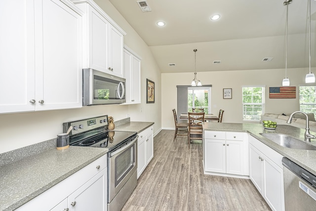 kitchen with visible vents, a sink, light wood-style flooring, appliances with stainless steel finishes, and vaulted ceiling