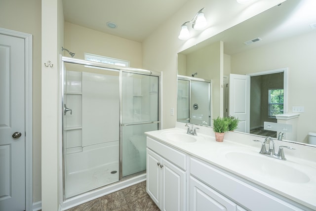 bathroom featuring visible vents, double vanity, toilet, a shower stall, and a sink