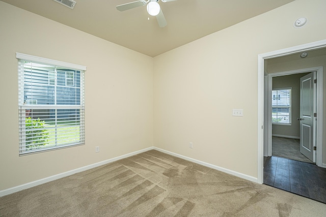 carpeted empty room featuring ceiling fan, visible vents, and baseboards
