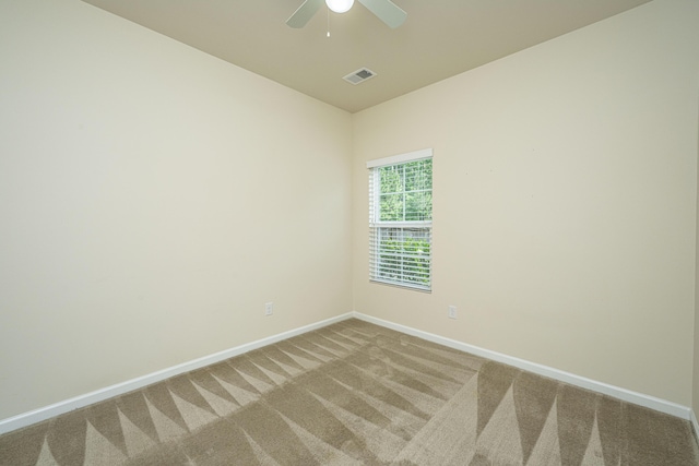 carpeted spare room with visible vents, baseboards, and ceiling fan
