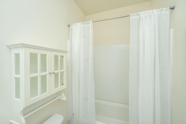 bathroom featuring shower / bath combination with curtain and toilet
