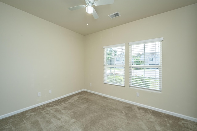 carpeted spare room with visible vents, a ceiling fan, and baseboards