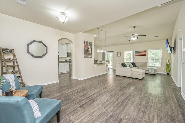 living area with arched walkways, ceiling fan, dark wood finished floors, and visible vents