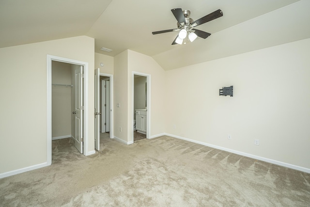 unfurnished bedroom with a walk in closet, carpet, baseboards, vaulted ceiling, and a closet