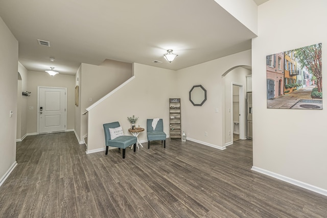 sitting room featuring arched walkways, baseboards, visible vents, and wood finished floors