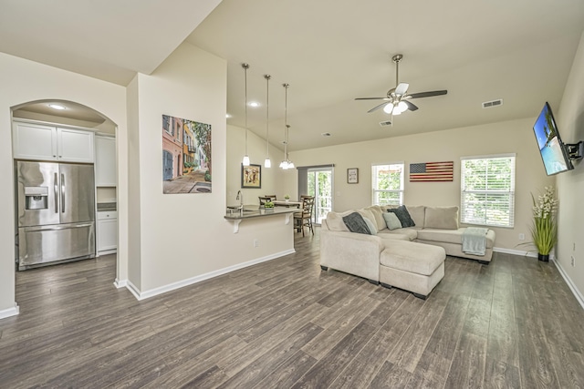 living room featuring baseboards, arched walkways, dark wood finished floors, and ceiling fan