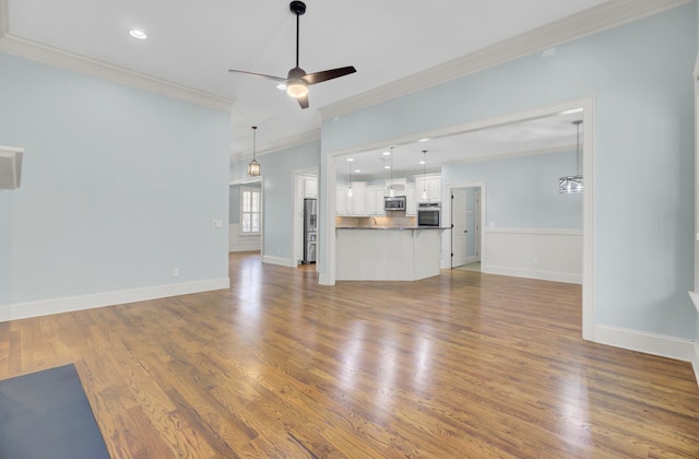 unfurnished living room featuring wood finished floors, recessed lighting, crown molding, baseboards, and ceiling fan