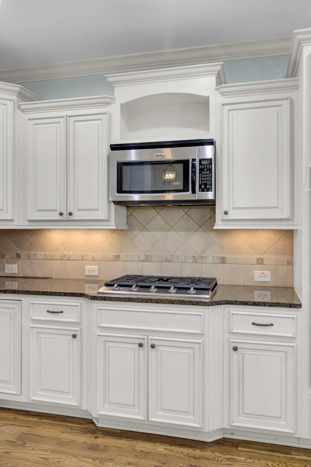 kitchen featuring backsplash, white cabinets, stainless steel appliances, and dark stone countertops