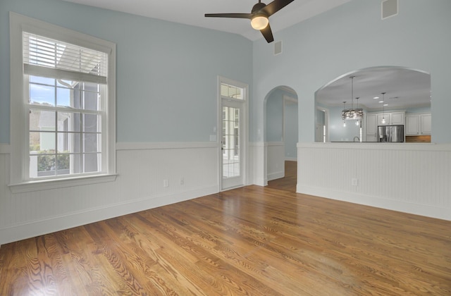 unfurnished living room featuring visible vents, wood finished floors, arched walkways, and ceiling fan