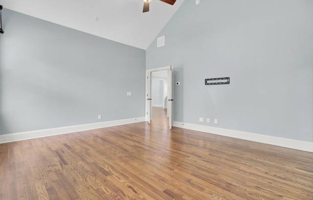 spare room featuring visible vents, high vaulted ceiling, wood finished floors, baseboards, and ceiling fan