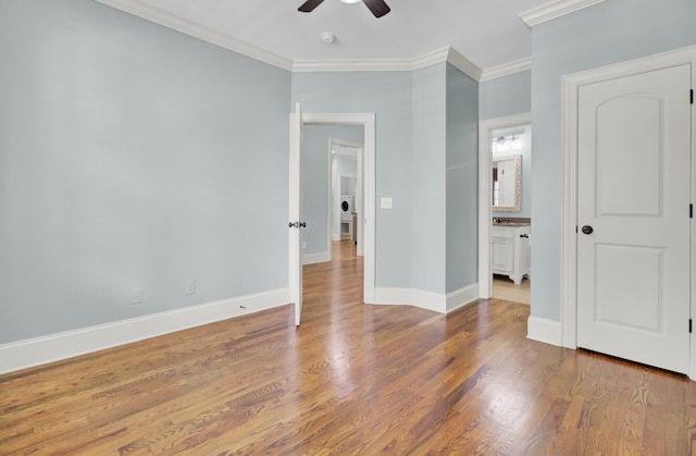 unfurnished bedroom featuring connected bathroom, baseboards, wood finished floors, and ornamental molding