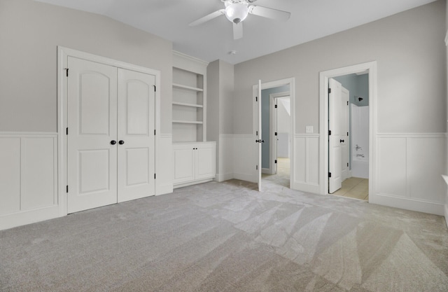 unfurnished bedroom with connected bathroom, carpet, a closet, and wainscoting