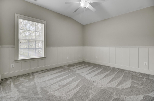 unfurnished room featuring vaulted ceiling, a ceiling fan, carpet floors, and wainscoting