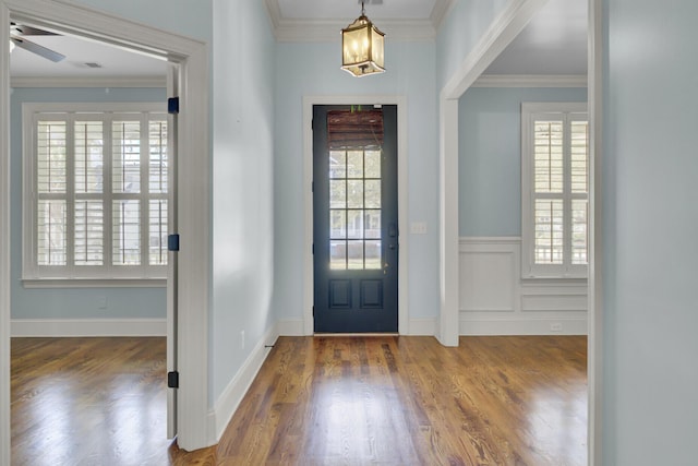 foyer with wood finished floors, a healthy amount of sunlight, and ornamental molding