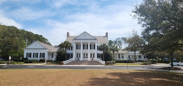 view of front of house featuring metal roof, a front lawn, and a chimney