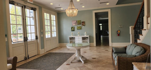 foyer entrance featuring a chandelier, a healthy amount of sunlight, ornamental molding, and stairs