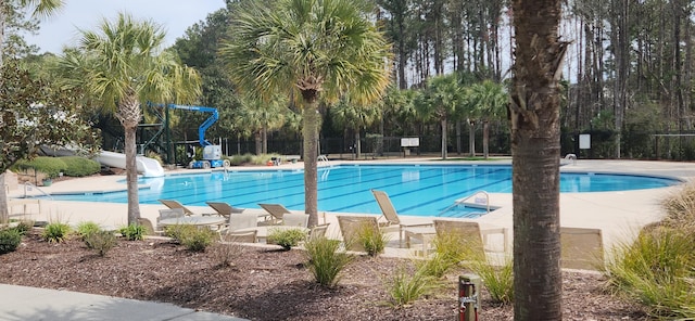 community pool featuring a water slide, a patio, and fence