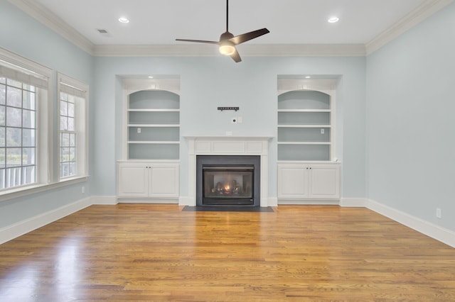 unfurnished living room with crown molding, built in shelves, and baseboards