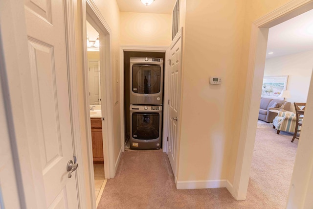 hall featuring stacked washer and clothes dryer, light carpet, and sink