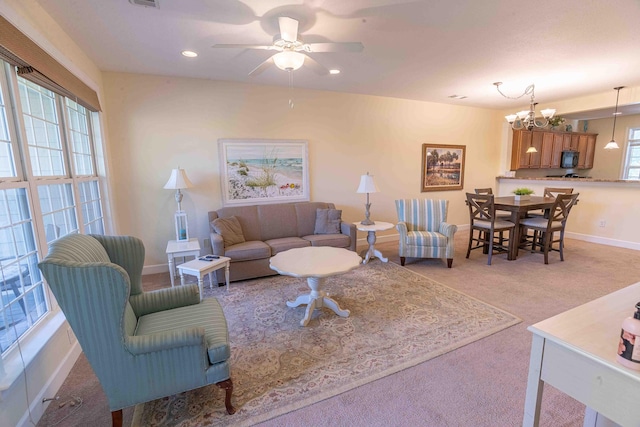 carpeted living room featuring ceiling fan with notable chandelier