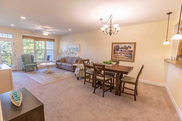 carpeted dining space featuring ceiling fan with notable chandelier