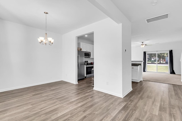 empty room with light hardwood / wood-style flooring and ceiling fan with notable chandelier