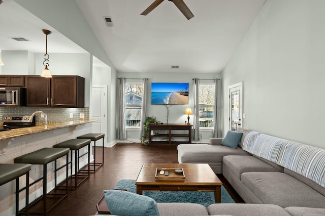 living area featuring dark wood finished floors, visible vents, high vaulted ceiling, and ceiling fan