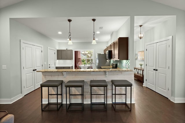 kitchen with a kitchen bar, appliances with stainless steel finishes, dark wood finished floors, and visible vents