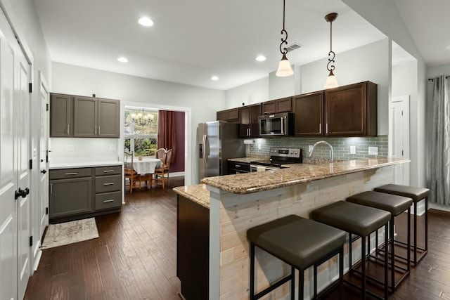 kitchen with tasteful backsplash, appliances with stainless steel finishes, a breakfast bar area, and dark wood finished floors