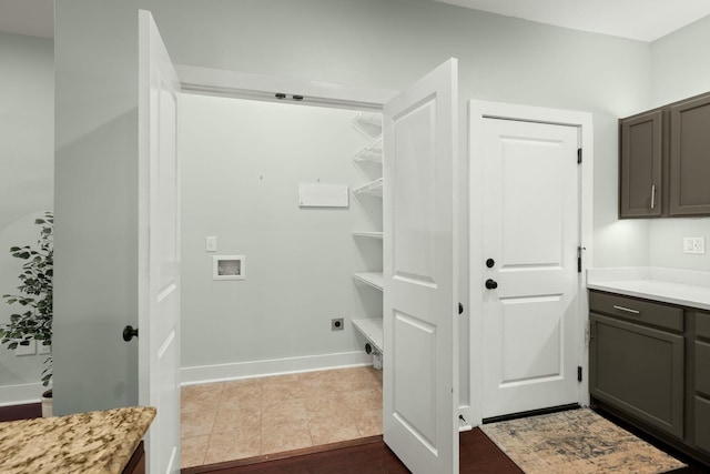 laundry room with electric dryer hookup, dark tile patterned flooring, cabinet space, baseboards, and hookup for a washing machine