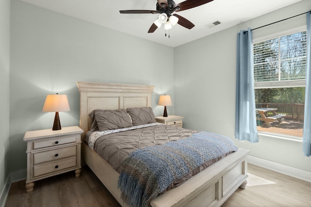 bedroom featuring ceiling fan, visible vents, baseboards, and wood finished floors