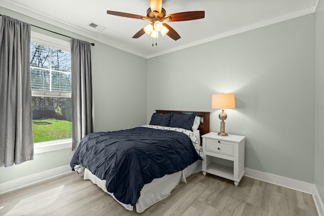 bedroom with visible vents, baseboards, ornamental molding, and light wood finished floors