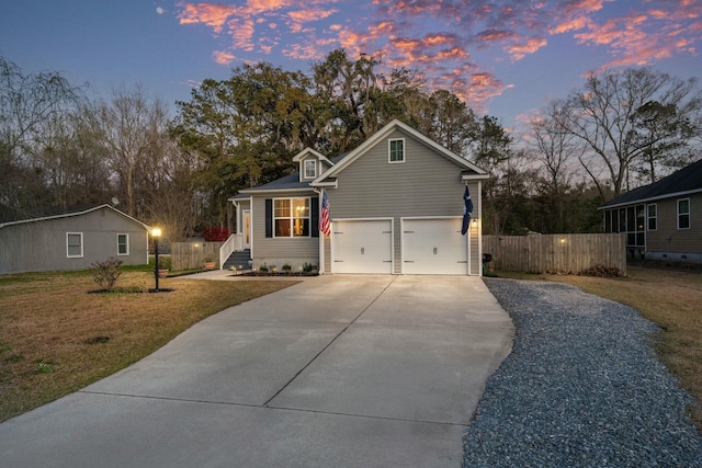 view of front of home featuring an attached garage, fence, a lawn, and driveway