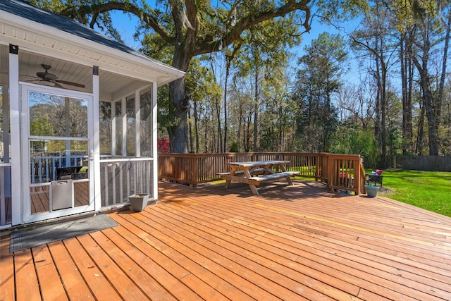 wooden deck featuring a lawn, a ceiling fan, and a sunroom