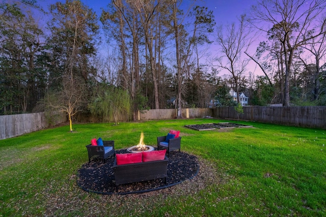 yard at dusk featuring a garden, a fire pit, and a fenced backyard