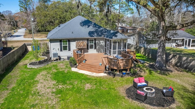 back of house with a wooden deck, a lawn, an outdoor fire pit, and a fenced backyard